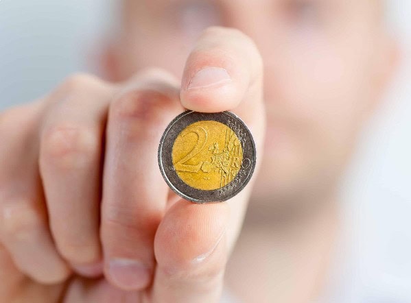 Närbild på en person som håller ett tvåeurosmynt – symboliserar hushållsavdraget på -35 % som går att få för hemvårdstjänster genom Finlands Seniorvård.