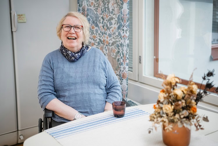 Suomen Seniorihoivan asiakas Arja hymyilee kahvipöydässä.