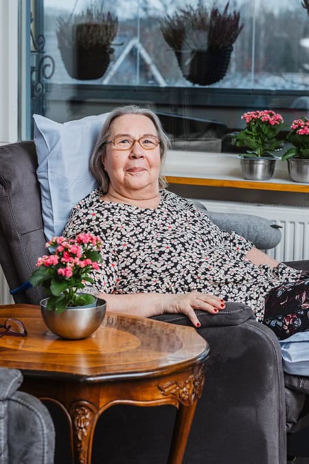 Suomen Seniorihoivan asiakas Pirkko hymyilee kahvipöydässä.