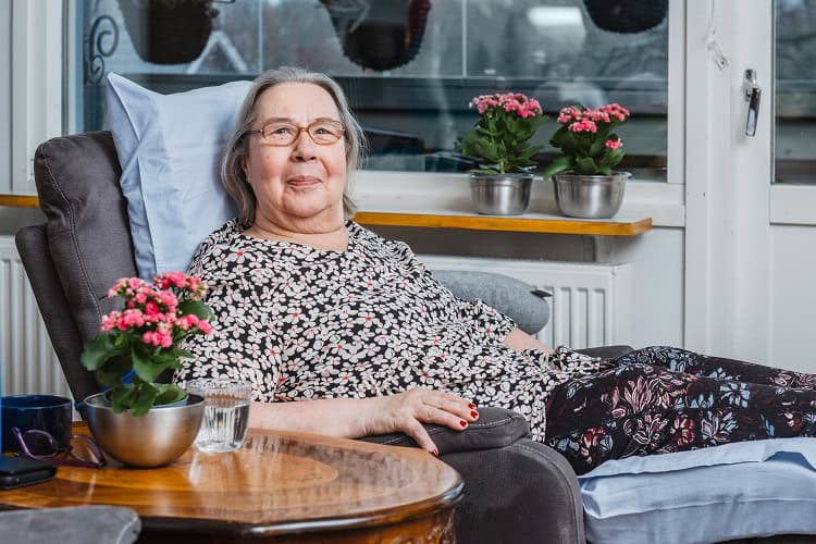 Suomen Seniorihoivan asiakas Pirkko hymyilee kahvipöydässä.