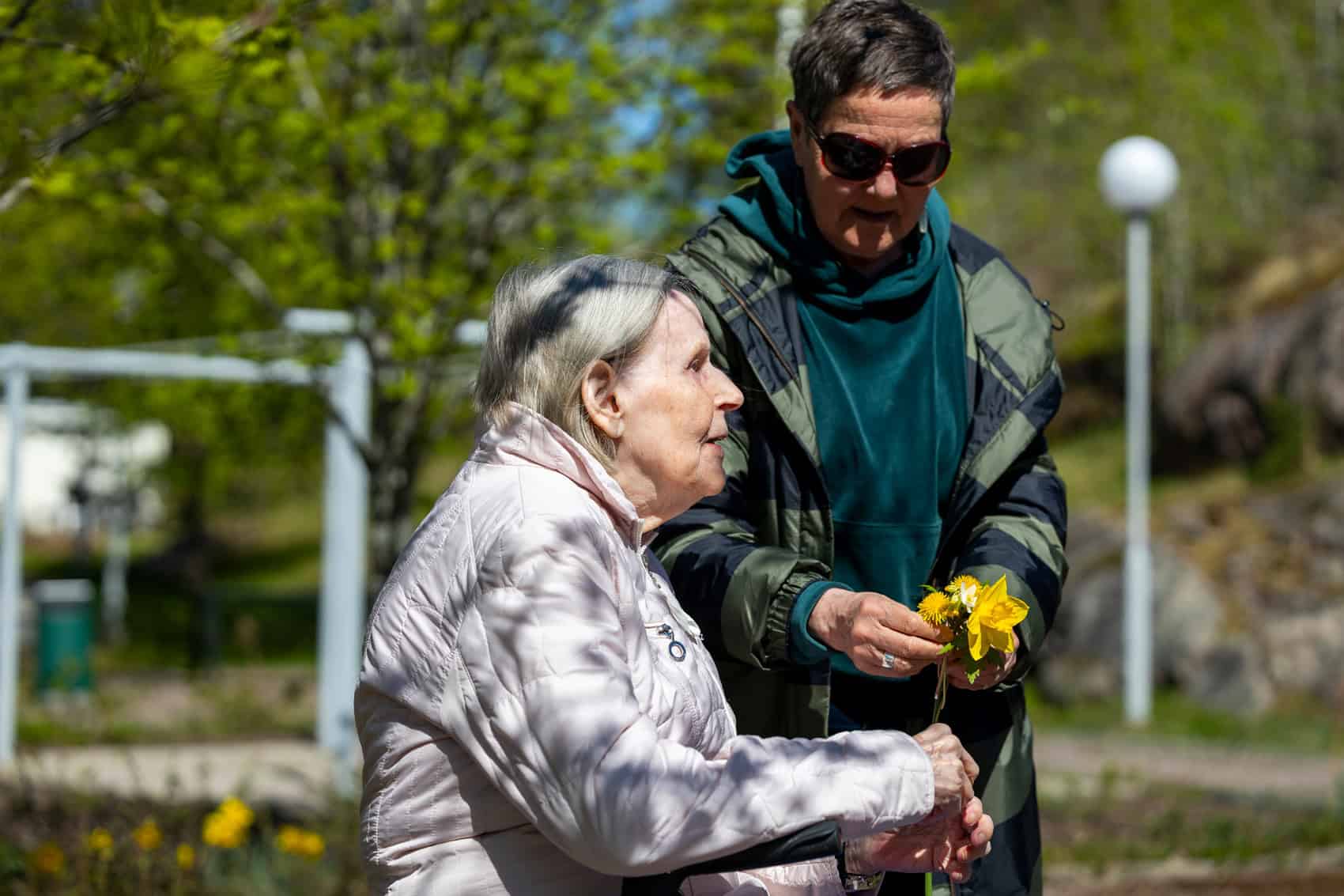 Ikäihminen ja hoitaja ulkoilemassa puistossa Suomen Seniorihoivassa.